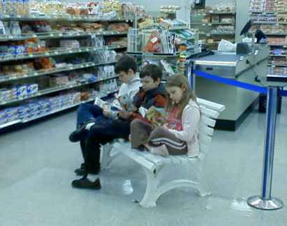 three children seated on a bench reading in the store